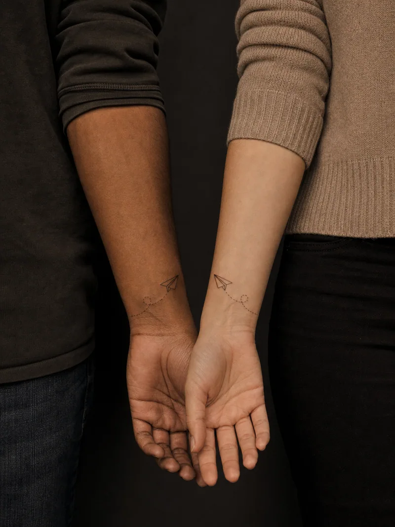 Matching paper airplane tattoos - Mirrored paper planes travel toward the center on short dotted paths.