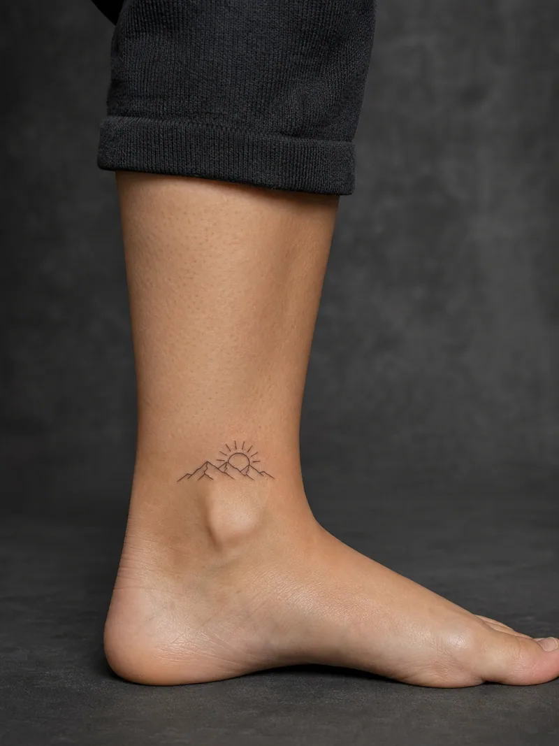 Tiny mountain tattoo - A small ridge and rising sun leave generous open skin.