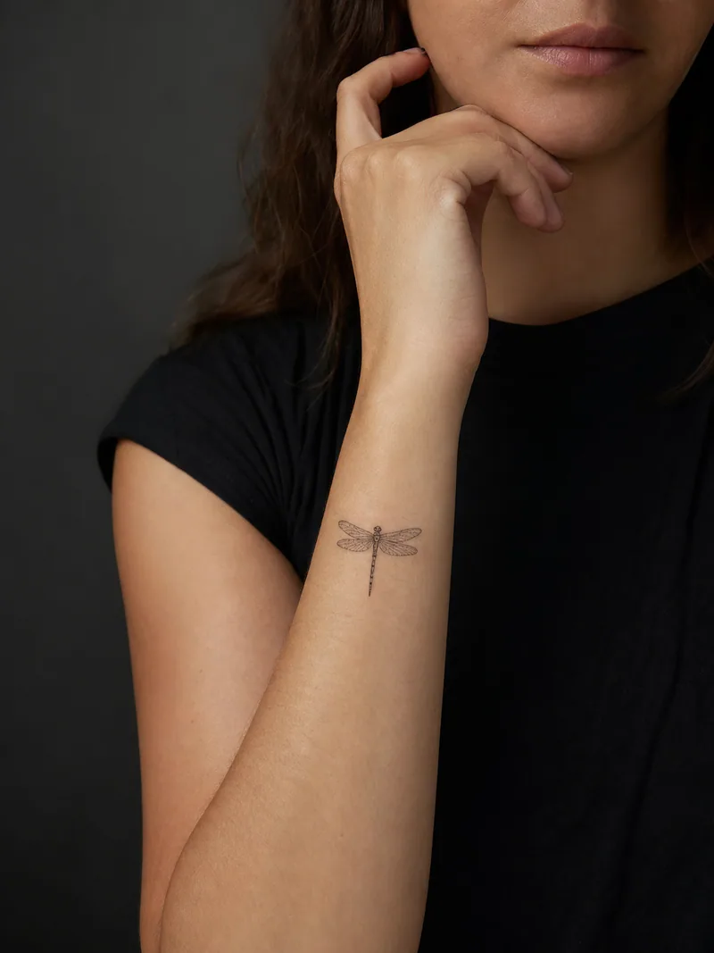 Fine-line dragonfly tattoo - Simplified wings and sparse dots keep the dragonfly clear.