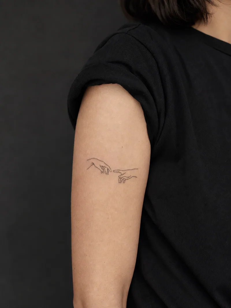 Fine-line hands tattoo - Two simplified hands nearly meet inside a clean open composition.