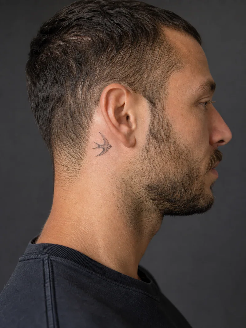 Tiny swallow tattoo - A side-flight swallow keeps a simple readable wing silhouette.