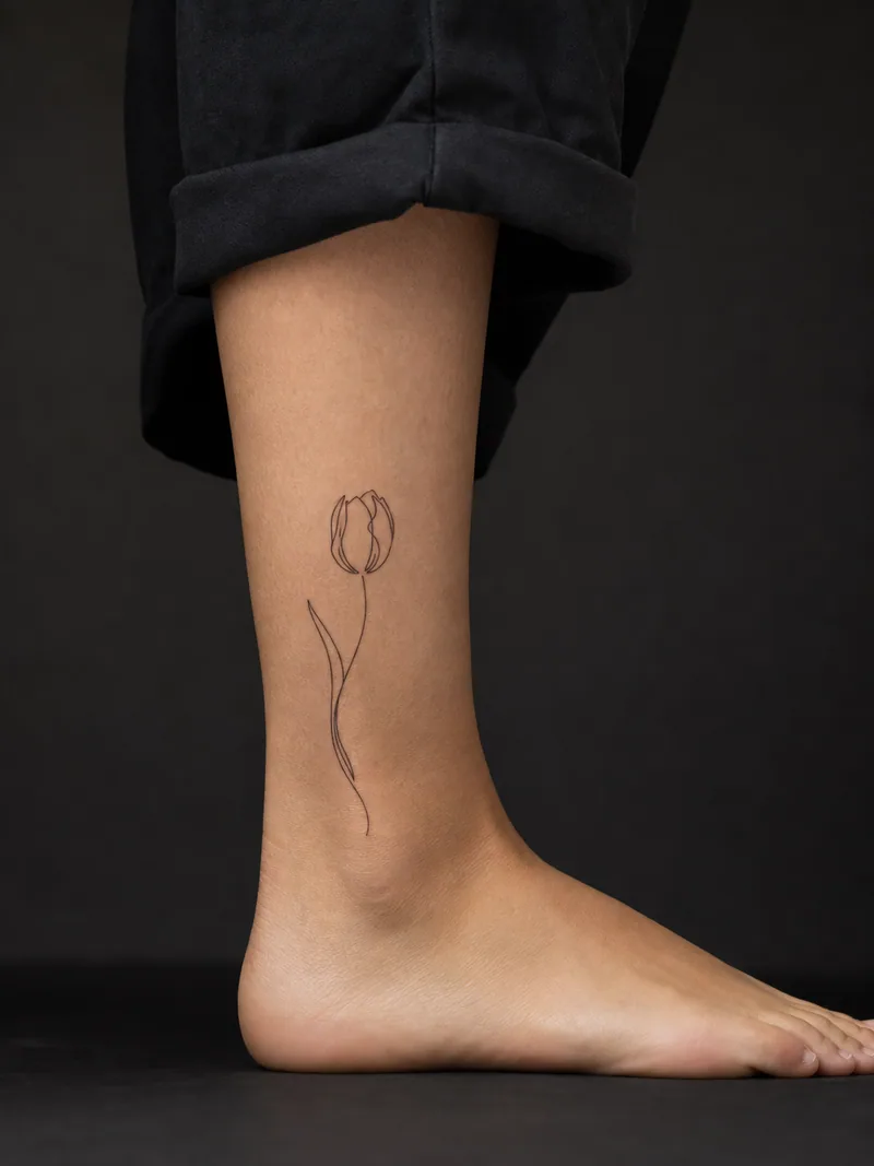 Single-line tulip tattoo - One continuous contour draws a tulip with generous negative space.