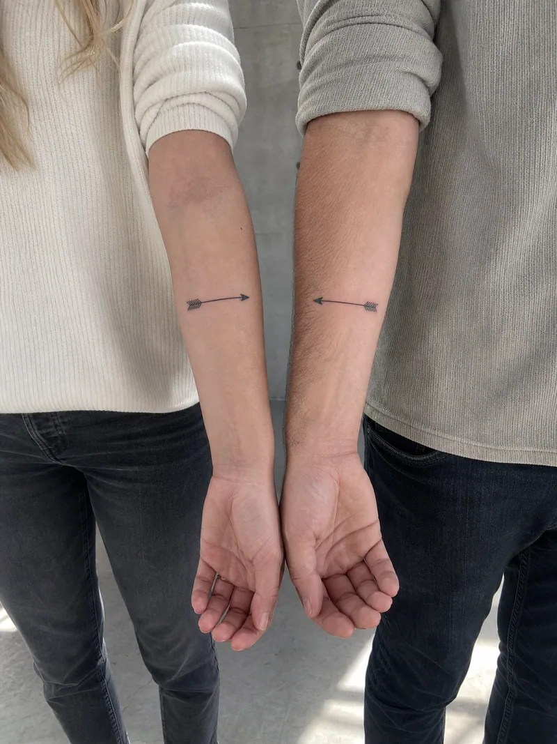 Matching arrow tattoos - two fine line arrows pointing toward each other