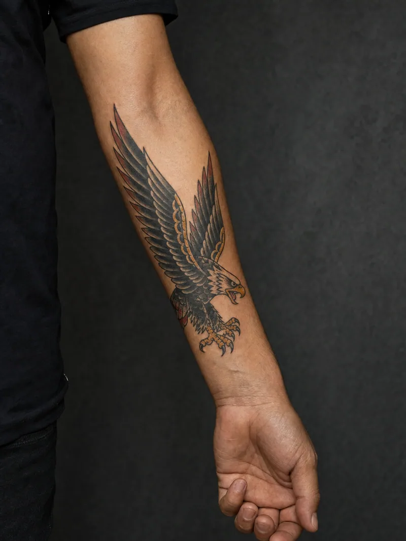 Traditional eagle forearm tattoo - Open wings create a bold tapered panel above the wrist.