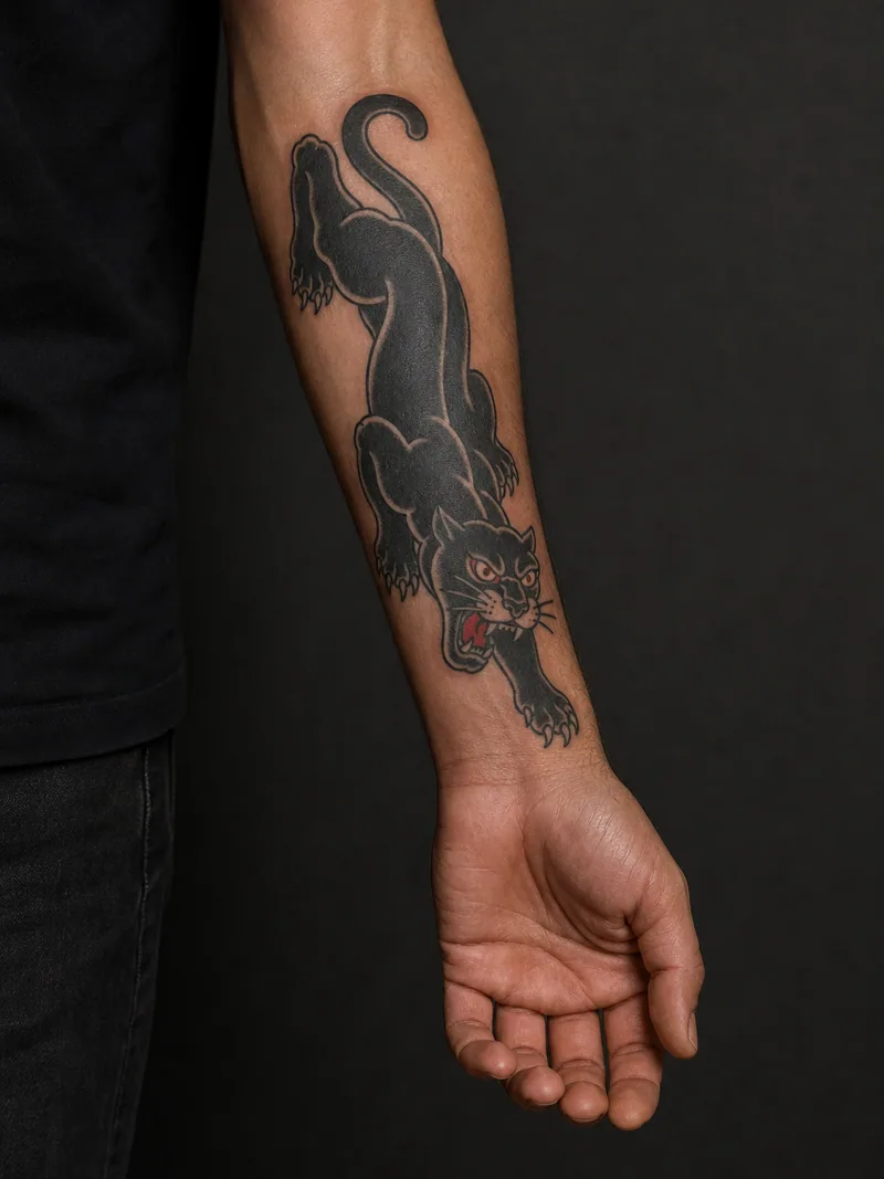 Panther forearm tattoo - A crawling panther follows the outer forearm with one red accent.