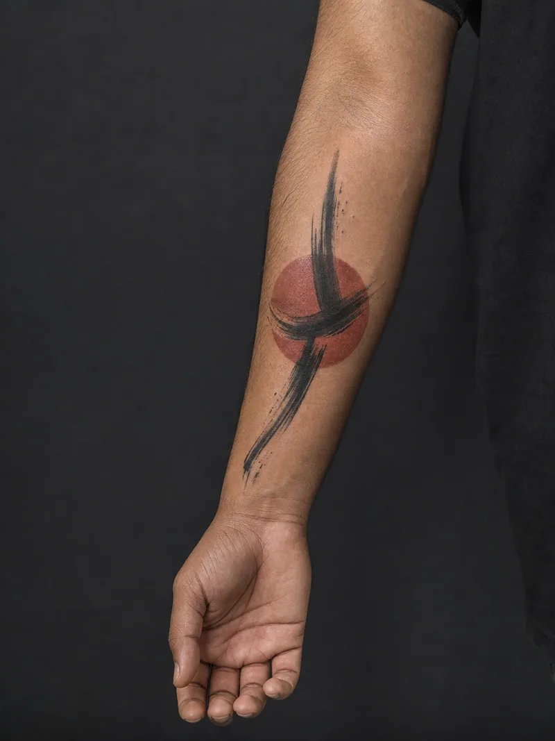 Abstract forearm tattoo - A black gesture crosses one rust circle with deliberate negative space.