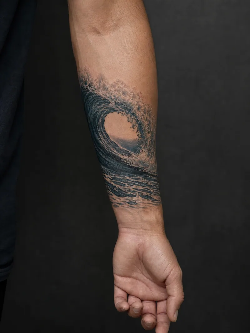 Ocean wave forearm tattoo - A cresting wave wraps lightly around the outer forearm.