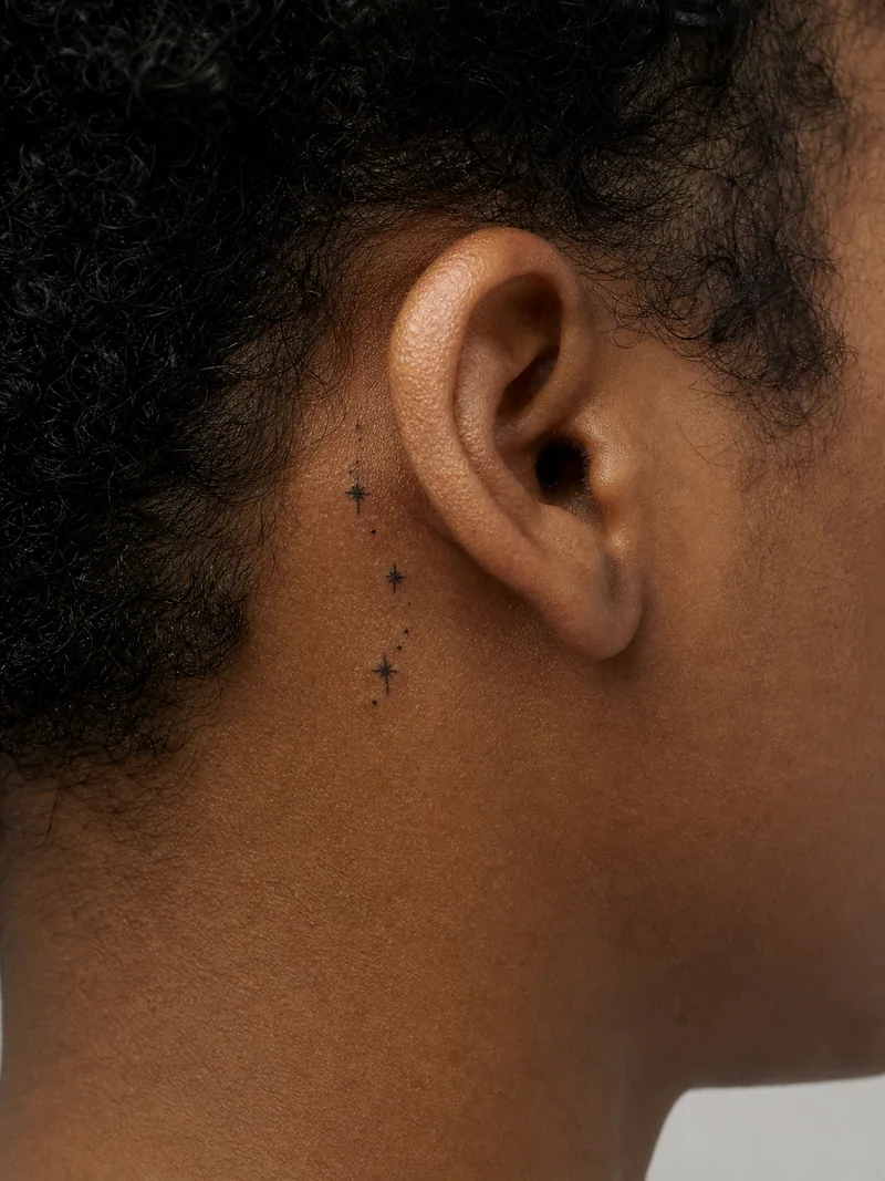 Stars behind ear tattoo - three tiny stars and dots following the natural curve behind the ear
