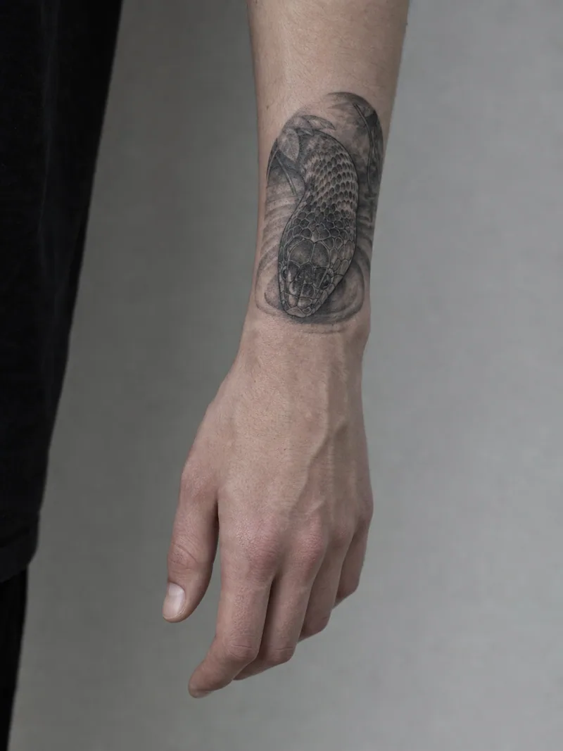 Realistic snake wrist tattoo - detailed snake head flowing from the lower forearm toward the wrist