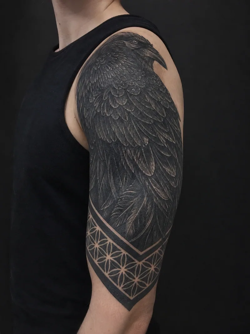 Raven cover-up tattoo - dense raven feathers transitioning into geometric bands over an older tattoo