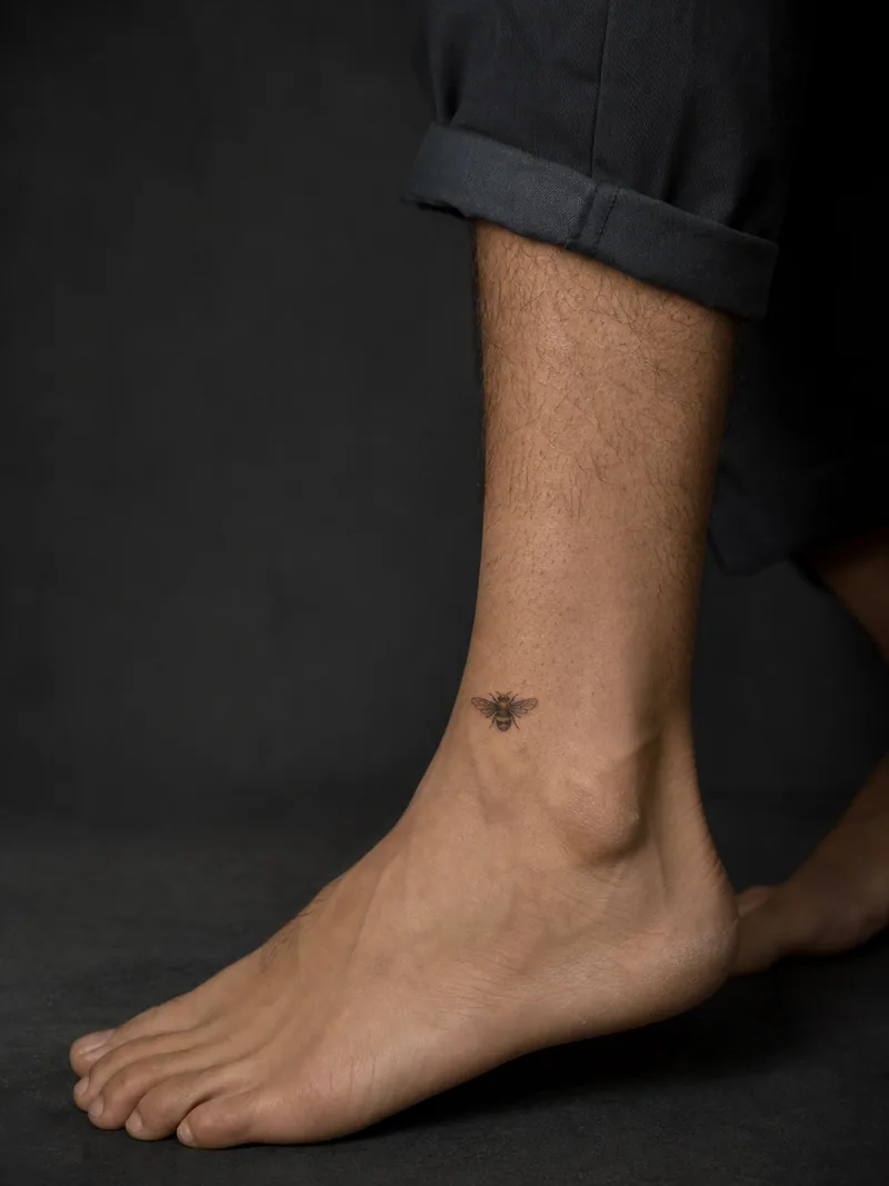 Tiny bee tattoo - small detailed bee placed above the ankle with clean skin around it