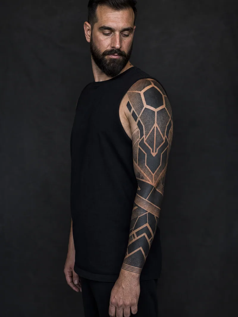 Geometric blackwork sleeve - Large polygons and dot gradients alternate with clean negative-space bands.