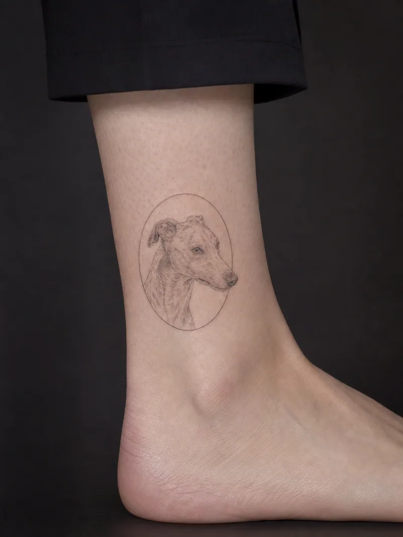 Greyhound portrait tattoo - a delicate greyhound head portrait contained inside a thin oval frame
