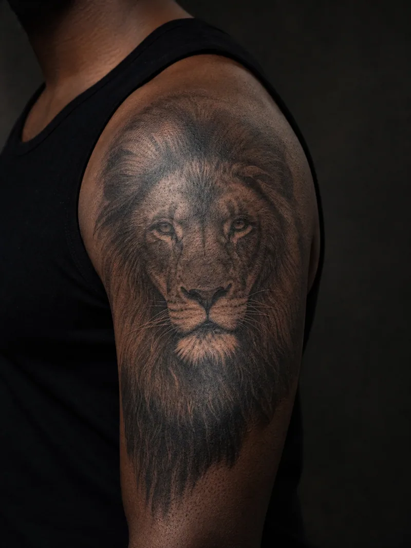 Realistic lion tattoo - a calm lion portrait with a detailed mane wrapping the shoulder