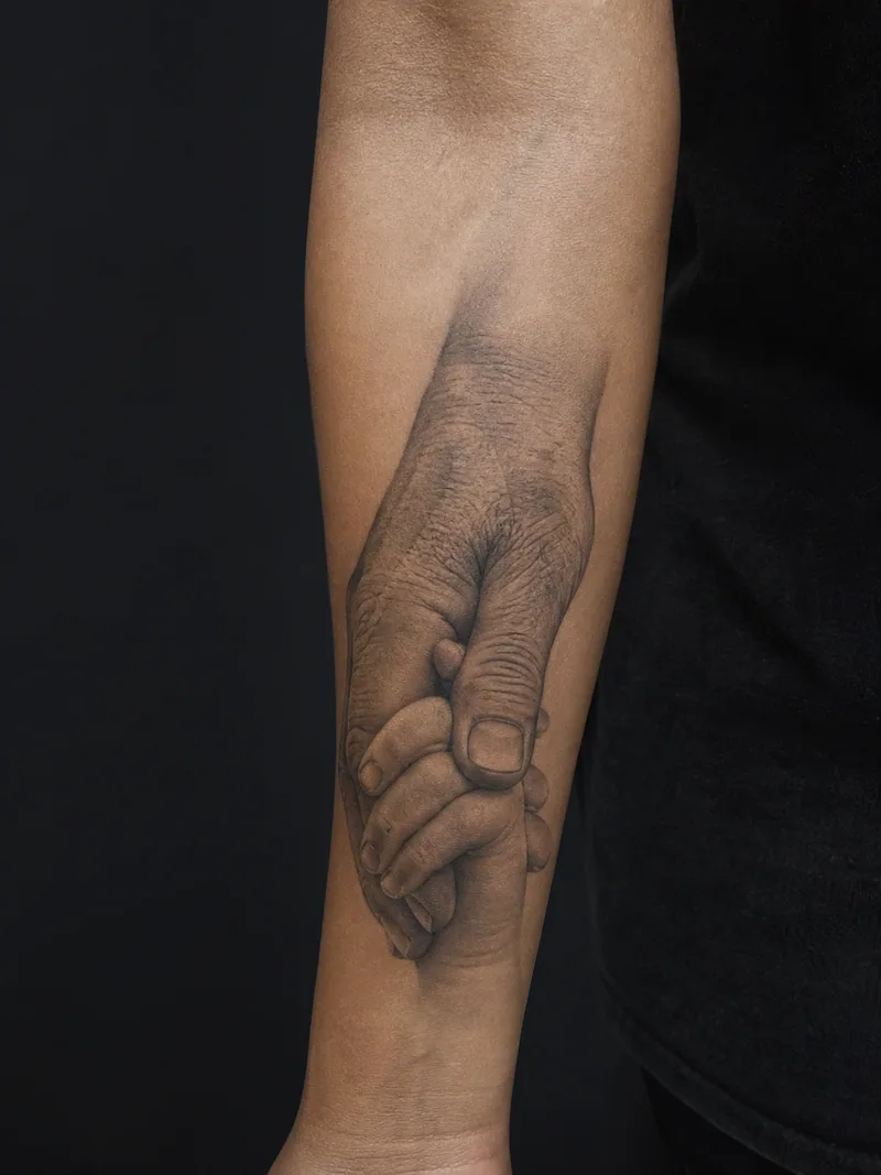 Family hands tattoo - an older hand gently holding a child hand