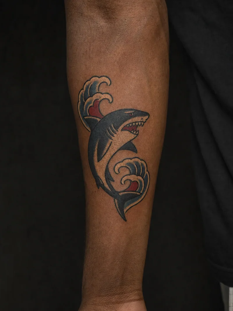 Traditional shark tattoo - a swimming shark cutting through two stylized waves