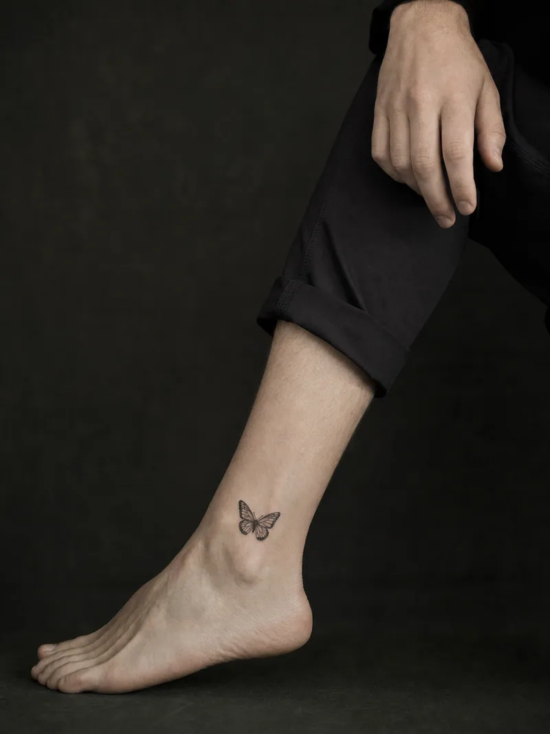 Tiny butterfly ankle tattoo - single small butterfly placed above the ankle with generous clean skin