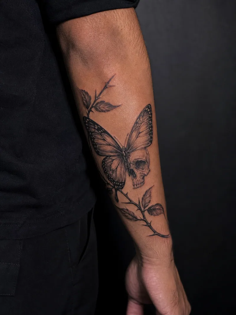 Skull butterfly tattoo - butterfly wing transitioning into a small skull among thorny leaves