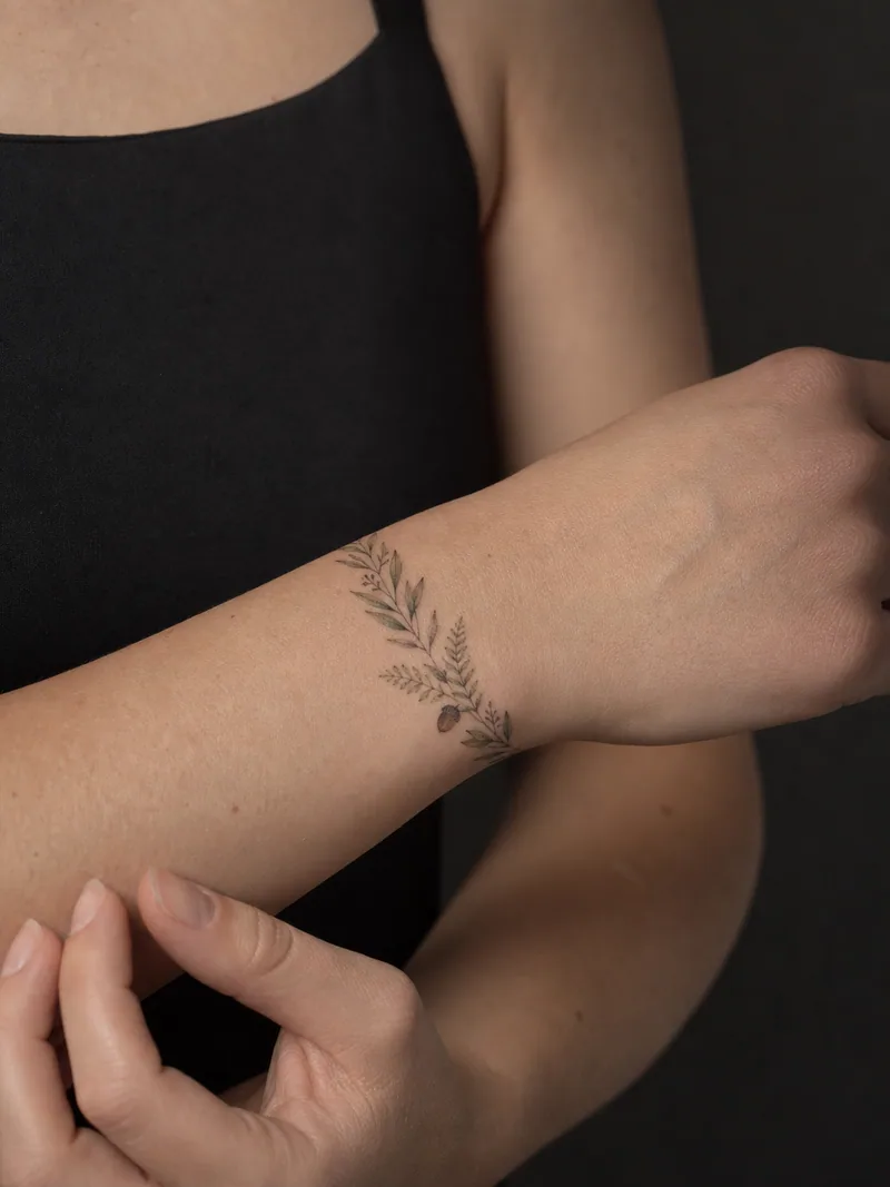 Leaf bracelet tattoo - olive leaves, tiny ferns and one acorn wrapping around the wrist