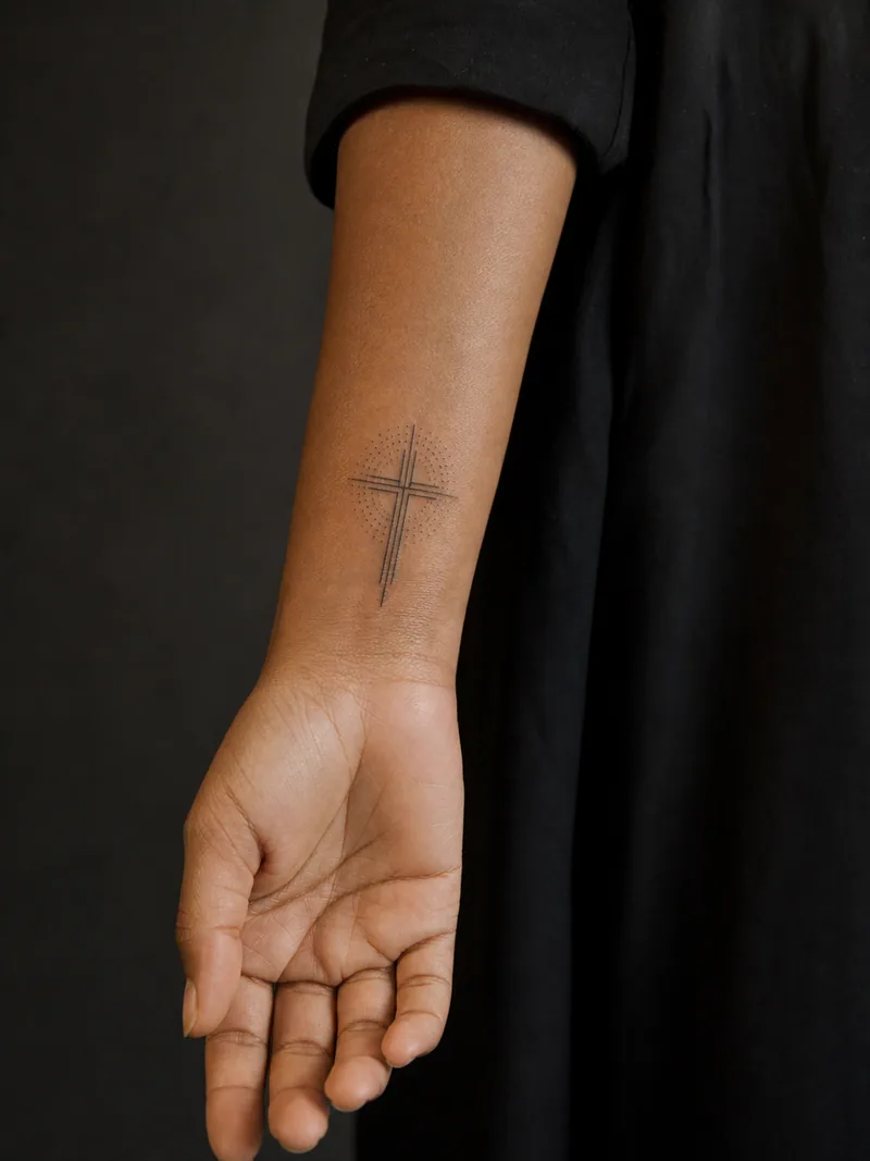 Small cross wrist tattoo - small cross built from precise intersecting lines and a dotwork halo
