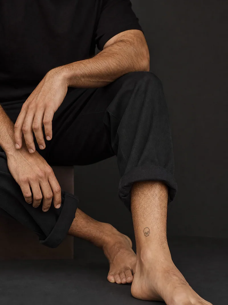 Tiny skull ankle tattoo - small friendly skull outline with generous clean skin around it