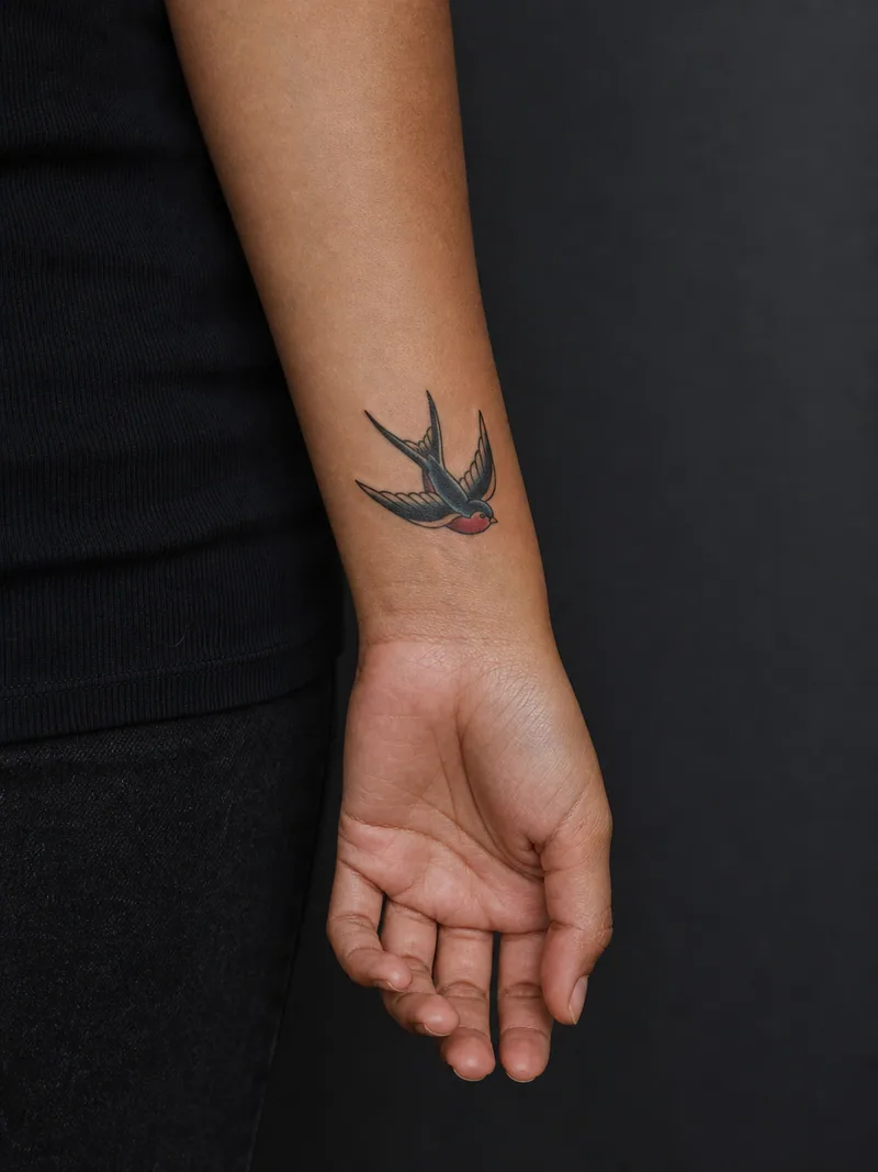 Traditional swallow tattoo - A compact flying swallow keeps classic color and bold readability.