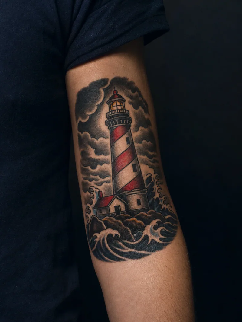 Traditional lighthouse tattoo - A striped lighthouse rises beneath compact storm clouds.