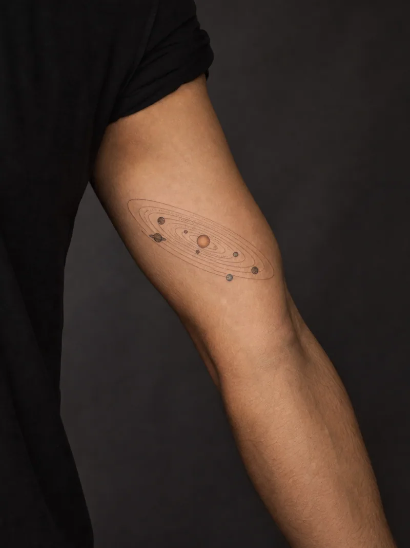 Solar system tattoo - Small planets follow clean curved orbits around one ochre sun.